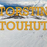 Kansikuva Torstin Touhut -kanavalle. Panoraamakuva lumisesta Lyngen-vuoristosta Norjassa. Kuvan etualalla avara laskettelurinne ja kaksi pientä vapaalaskijaa. Taustalla näkyy vuono ja vuoria. Keskellä kuvaa oranssilla tekstillä Torstin Touhut